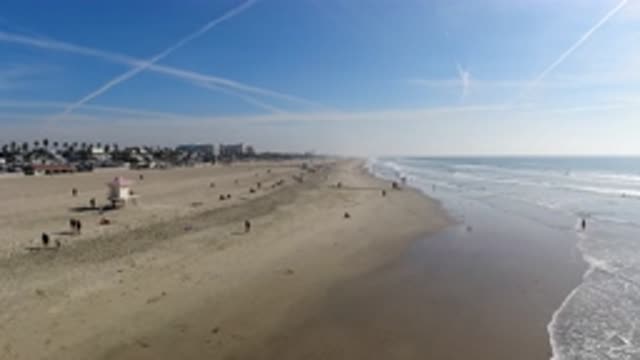 HUNTINGTON BEACH CALIFORNIA-2019: Waves Roll In On Shore People On Beach Stroll