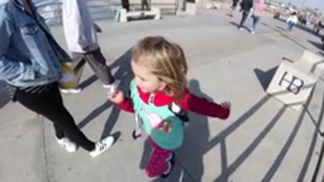 HUNTINGTON BEACH CALIFORNIA-2019: Little Girl In Pink Running In Slow Motion On Boardwalk