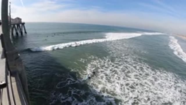 HUNTINGTON BEACH CALIFORNIA-2019: Pier To The Left Waves Roll Toward Shore