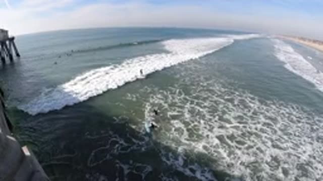 HUNTINGTON BEACH CALIFORNIA-2019: Pier To The Left Waves Roll Toward Shore To