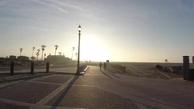 HUNTINGTON BEACH CALIFORNIA-2019: Two People Running Across a Bridge at Sunset