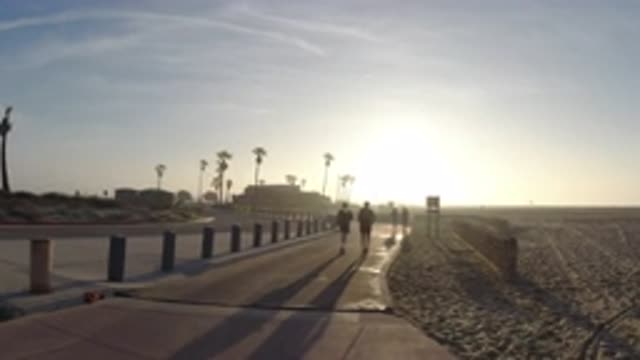 HUNTINGTON BEACH CALIFORNIA-2019: People Jogging On A Sidewalk Near A Beach