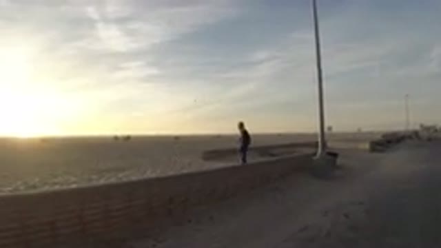 BOLSA CHICA CALIFORNIA-2019: Person Walking Along Seawall At Sunset