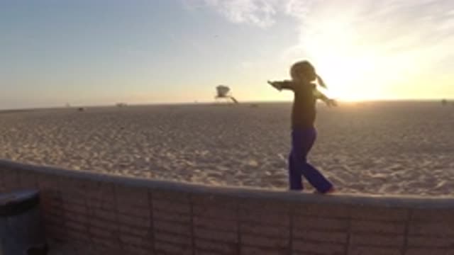 BOLSA CHICA CALIFORNIA-2019: Little Girl Tries Balancing On Thin Wall At Beach