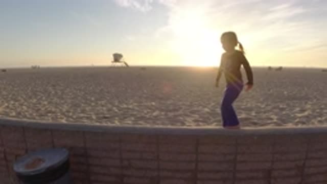 BOLSA CHICA CALIFORNIA-2019: A Young Girl Playing On A Wall On The Beach With