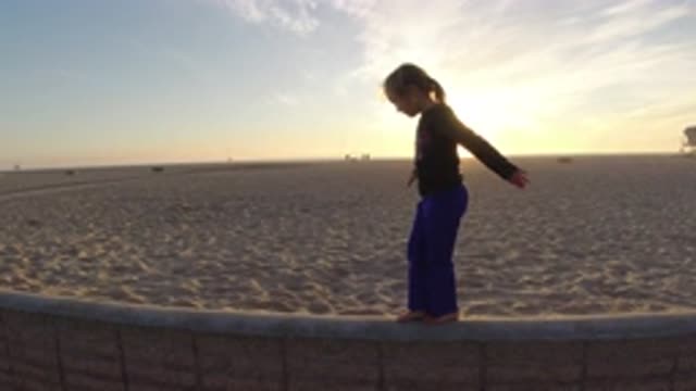BOLSA CHICA CALIFORNIA-2019: Small Girl Walking On A Short Wall On The Beach