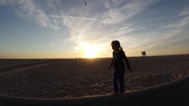 BOLSA CHICA CALIFORNIA-2019: Little Girl In Silhouette Standing On The Beach At Sunset