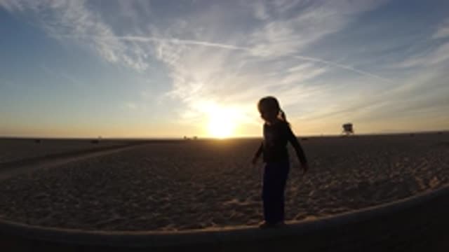 BOLSA CHICA CALIFORNIA-2019: Rural Girl Walks Beam With Sunset And Jet Trails In