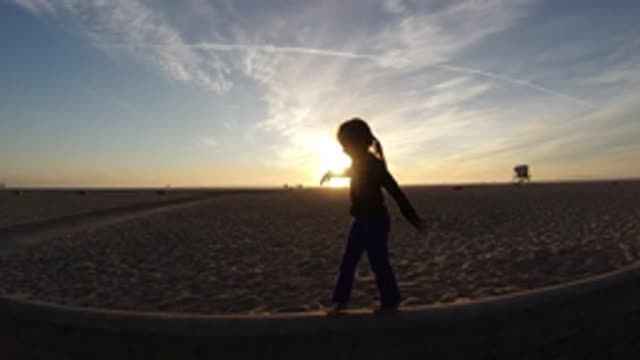 BOLSA CHICA CALIFORNIA-2019: A Person Walking Across A Ledge At Sunset