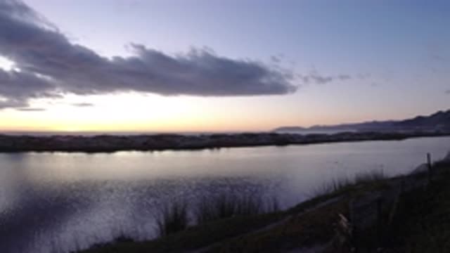 PISMO BEACH CALIFORNIA-2019: Sun Setting Behind Calm Lake On A Clear Day
