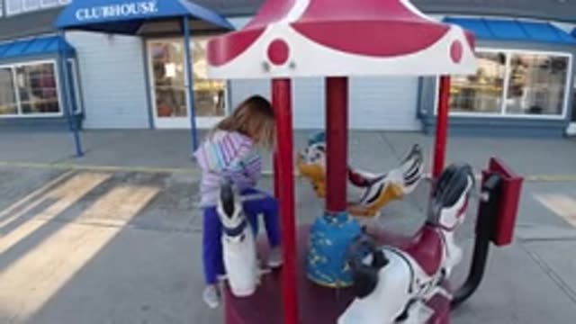PISMO BEACH CALIFORNIA-2019: Small Child in Hood Rides Backwards on a Merry-Go-Round