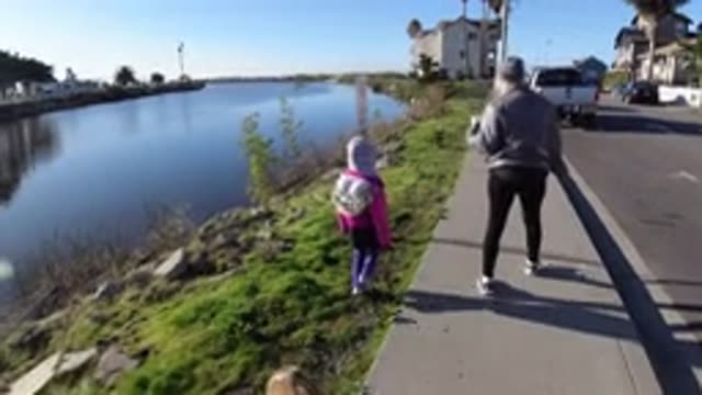 PISMO BEACH CALIFORNIA-2019: Mom And Daughter Walking By A River With Houses