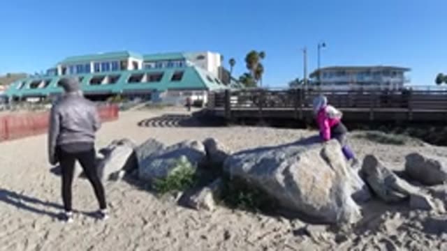 PISMO BEACH CALIFORNIA-2019: A Child Playing On A Rock While Mom Watches