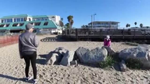 PISMO BEACH CALIFORNIA-2019: One Person in Pink Leans on a Stone by the Beach