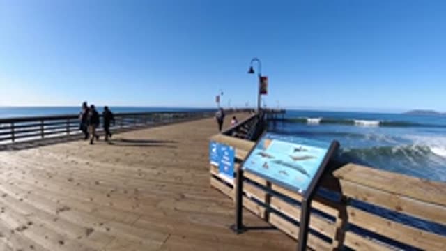 PISMO BEACH CALIFORNIA-2019: Three Adults and a Child Walk Along the Shore at Sunset