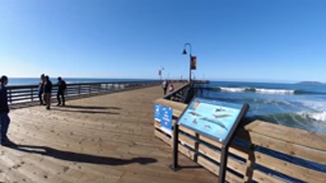 PISMO BEACH CALIFORNIA-2019: People Walk On Wooden Pier In Slow Motion Waves