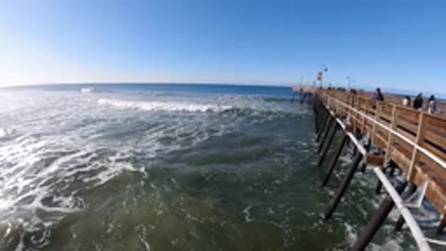PISMO BEACH CALIFORNIA-2019: Slow Motion Waves Roll Toward Shore People Walk On
