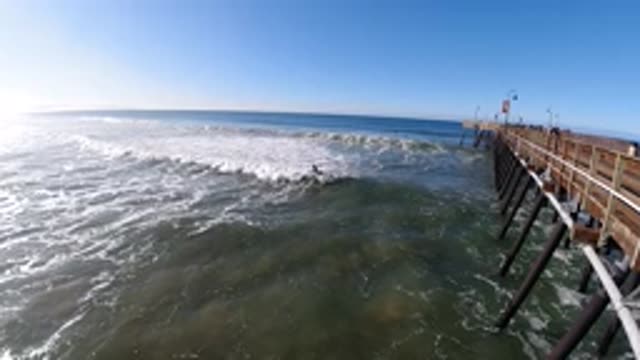 PISMO BEACH CALIFORNIA-2019: Surfer In The Waves Near A Pier