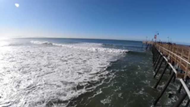 PISMO BEACH CALIFORNIA-2019: Wooden Pier To The Right Waves Roll Towards Shore