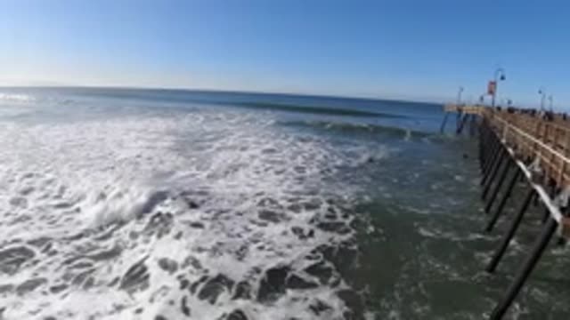 PISMO BEACH CALIFORNIA-2019: Waves Roll In Toward Shore Past Pier Over Water