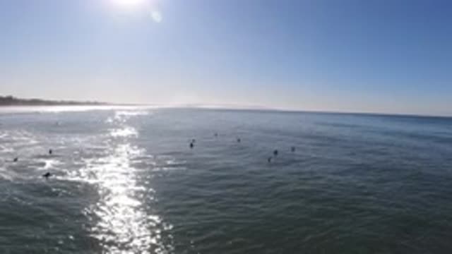 PISMO BEACH CALIFORNIA-2019: Surfers Hang Offshore From A Beach In The Late Afternoon