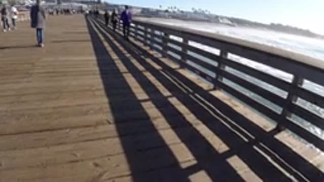 PISMO BEACH CALIFORNIA-2019: Several People Walking On A Long Bridge On A Sunny Day
