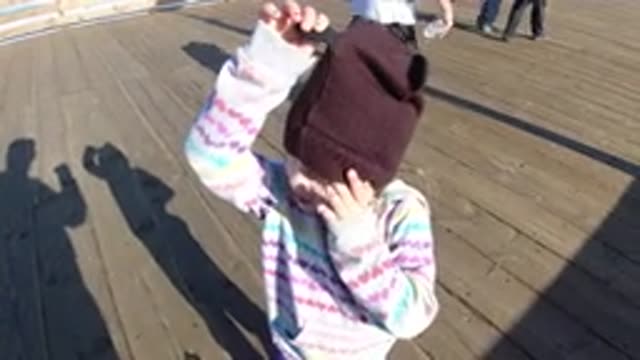 PISMO BEACH CALIFORNIA-2019: A Child Wearing A Striped Shirt And A Beanie Is Standing On A Dock
