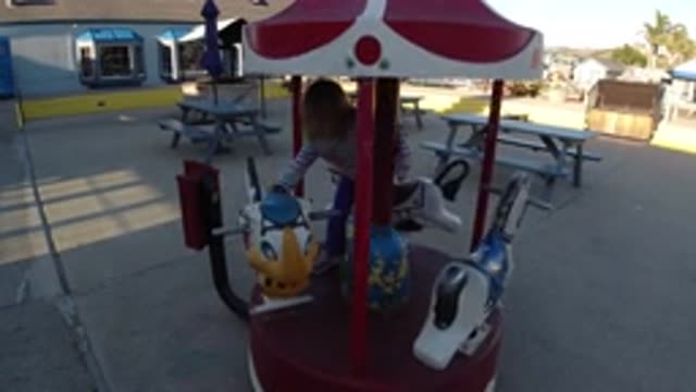 PISMO BEACH CALIFORNIA-2019: Young Girl Switching Seats On A Miniature Merry-Go-Round