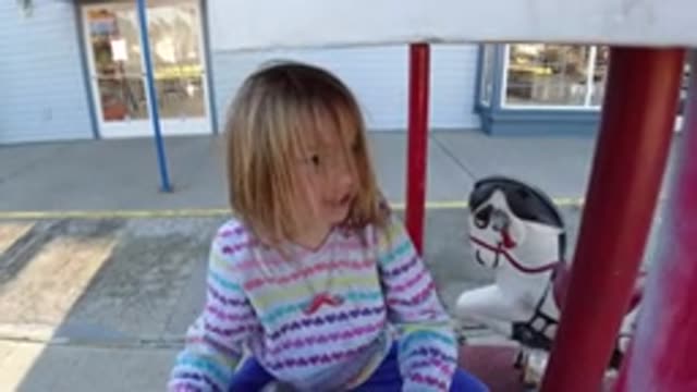 PISMO BEACH CALIFORNIA-2019: A Child In A Rainbow Hoodie On A Horse Going Around