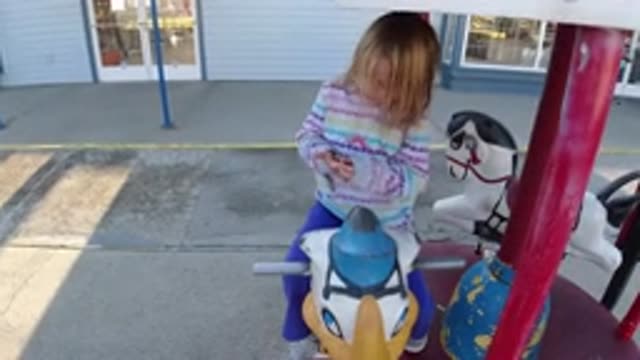 PISMO BEACH CALIFORNIA-2019: Little Girl Sitting On A Merry Go Round With Mom