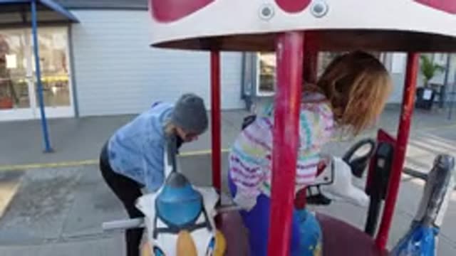 PISMO BEACH CALIFORNIA-2019: A Girl And A Lady Trying To Ride On The Merry Go