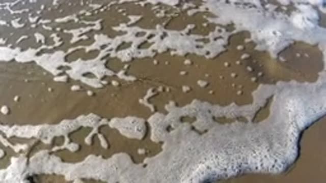 PISMO BEACH CALIFORNIA-2019: Foaming Water Washes Up On Shore Shadow Of Person