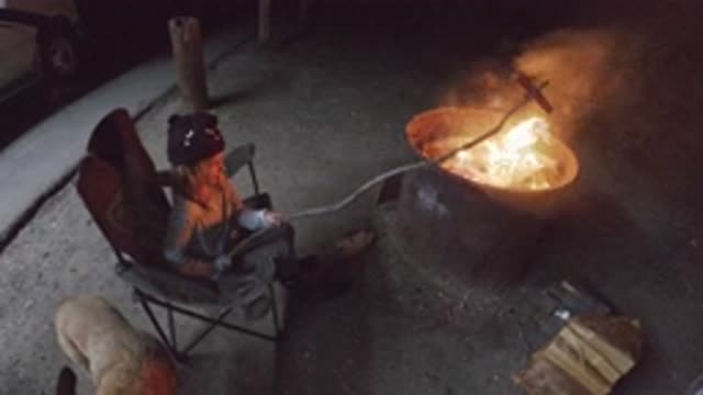 SAN CLEMENTE CALIFORNIA-2019: Woman In Beanie Holding Giant Stick Over Fire To Roast Sausage