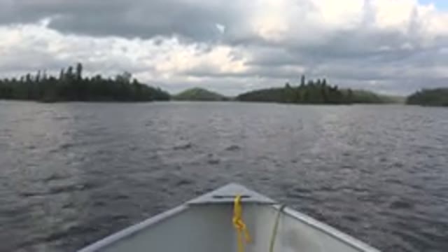 RED LAKE CANADA-2015: A Boat Is Speeding Down A Blue Body Of Water And There Is