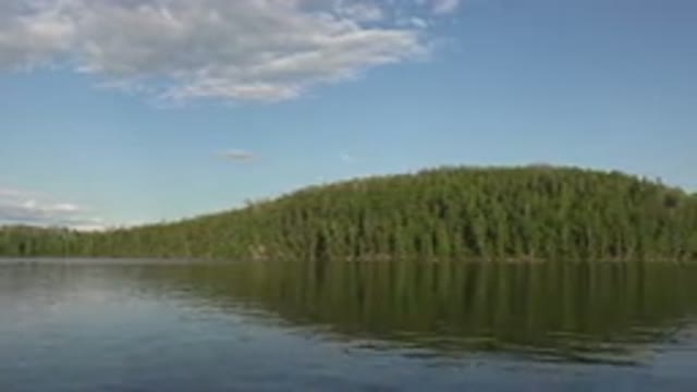 RED LAKE CANADA-2015: Water At A Lake With A Very Green Hill In The Background