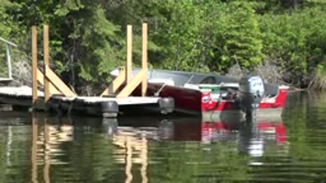 RED LAKE CANADA-2015: Boat On A River Moored To A Dock On A Sunny Day
