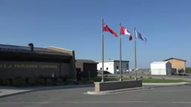 RED LAKE CANADA-2015: Gray Building Next To Three Different Flags Waving In The Wind
