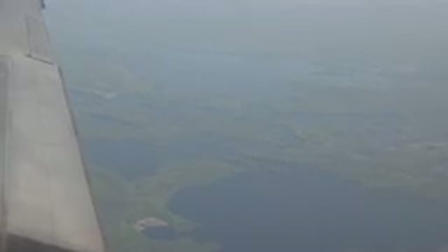 RED LAKE CANADA-2015: View Out Airplane Window of Wing, Land Masses and Water