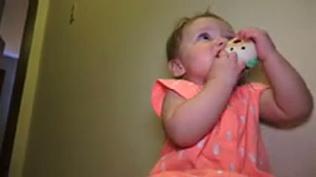 BROOMFIELD COLORADO-2015: Baby Wearing Orange Shirt Chews On White And Green Object