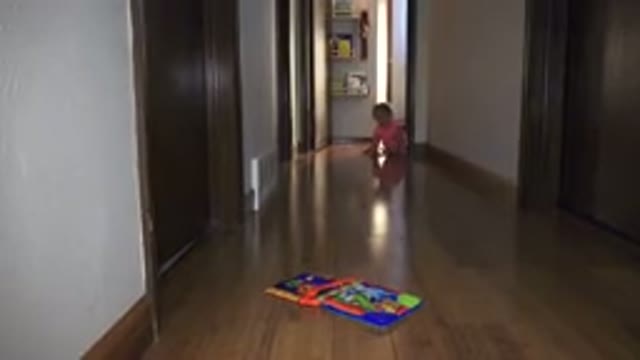 BROOMFIELD COLORADO-2015: Distant Toddler Wearing Orange Shirt Sitting On Hardwood Floor