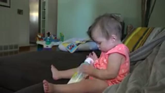 BROOMFIELD COLORADO-2015: A Little Toddler Sitting On A Bed Or Couch Has She
