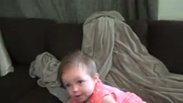 BROOMFIELD COLORADO-2015: Baby On Maroon Couch With Grey Blanket Tries To Pick