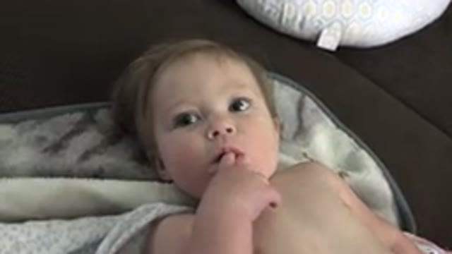 WESTMINSTER COLORADO-2015: Baby Lying With Finger in Mouth Smiling as Person Interacts