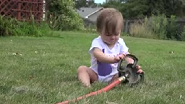 WESTMINSTER COLORADO-2015: Cute Girl Sitting On The Grass And Playing With The Hose