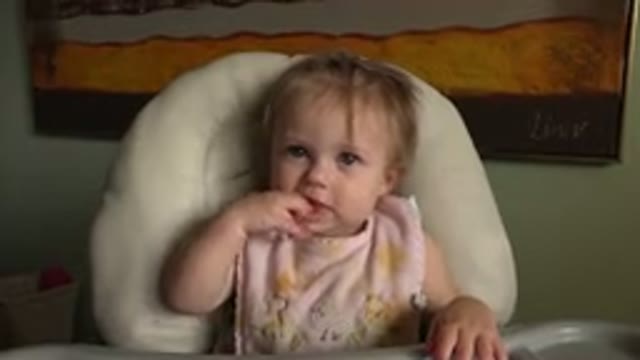 HIDDEN LAKE COLORADO-2015: Female Infant Sitting in High Chair Touching Mouth