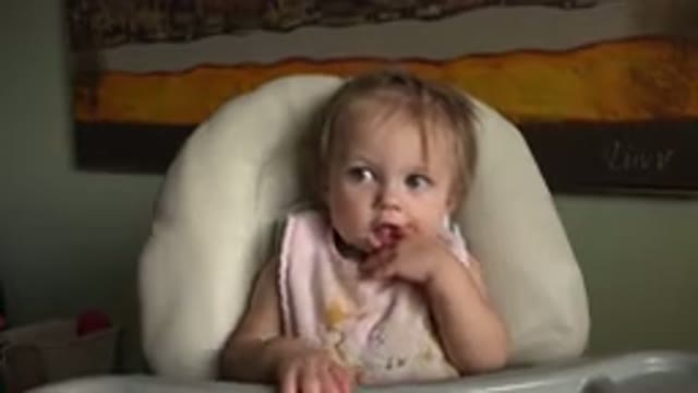 HIDDEN LAKE COLORADO-2015: Toddler Wearing Pink Bib Sits in White Padded Highchair