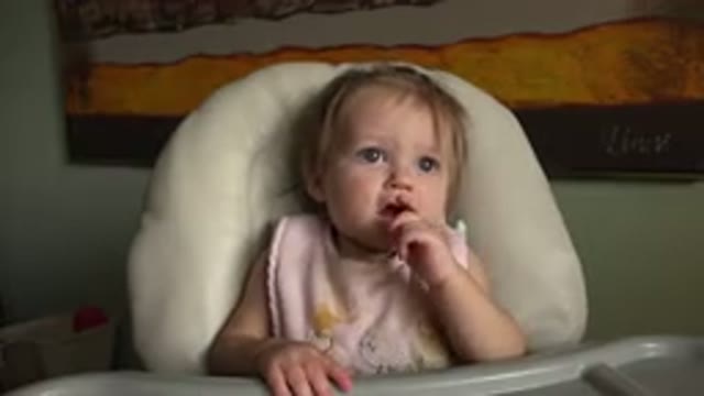 HIDDEN LAKE COLORADO-2015: An Active Toddler Wearing Pink Bib Sits In White Highchair