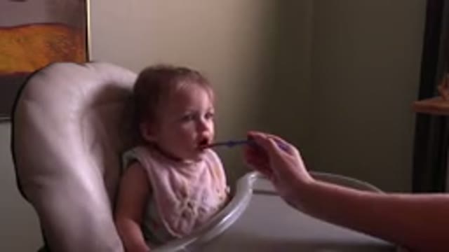 HIDDEN LAKE COLORADO-2015: Bib Wearing Baby Girl Eating From A Purple Spoon