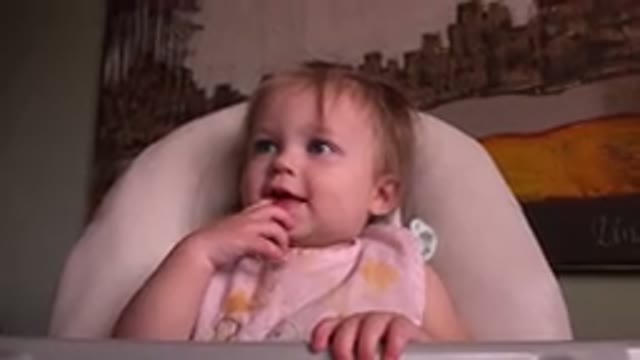 HIDDEN LAKE COLORADO-2015: A Baby Wearing A Bib Behind A Painting Sticking Her Tongue Out