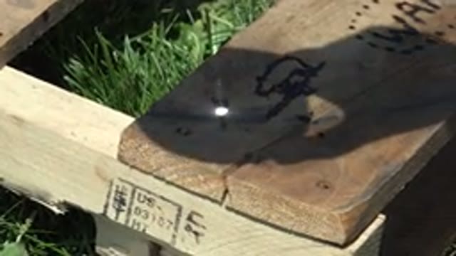 DENVER COLORADO-2015: Person Uses Sunlight Shining Through Magnifying Glass To Burn Wood